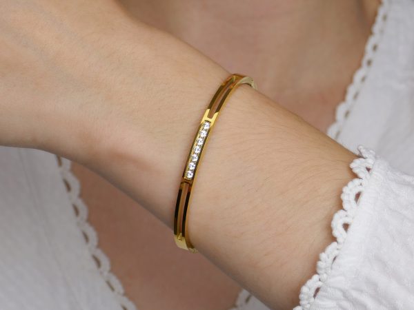 Jonc articulé rehaussé d'oxydes de zirconium blancs en acier inoxydable doré